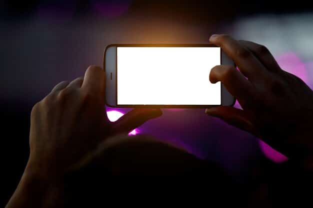 A person holding a smartphone displaying the Snapchat Spotlight screen. The screen shows a trending Spotlight challenge with several user submissions visible, showcasing varying themes and creative expressions. The focus is on the mobile screen, with blurred background elements to emphasize the content being viewed.